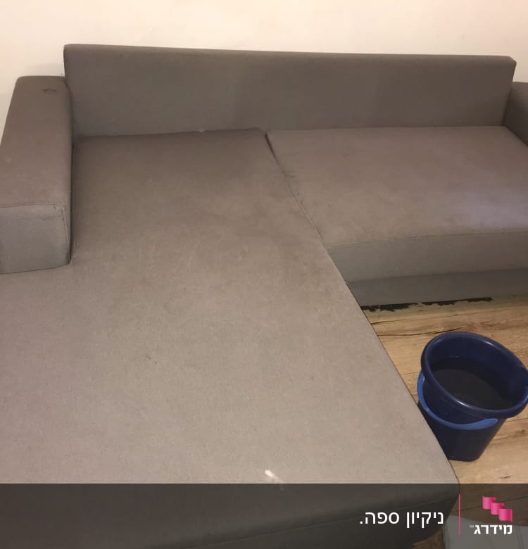 ספה אפורה עם דלי מים כחול על הרצפה